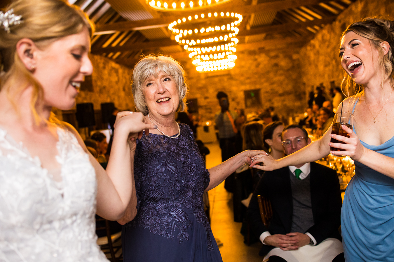 candid moment of the bride and her sister dancing with their mom during this fun, unique indoor wedding reception 