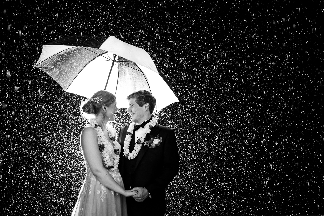 Elizabeth Furnace Wedding photographer, rhinehart photography, captures this black and white image of the bride and groom as they hold hands and smile at one another under neath the umbrella to avoid their rainy wedding weather in lititz pa 