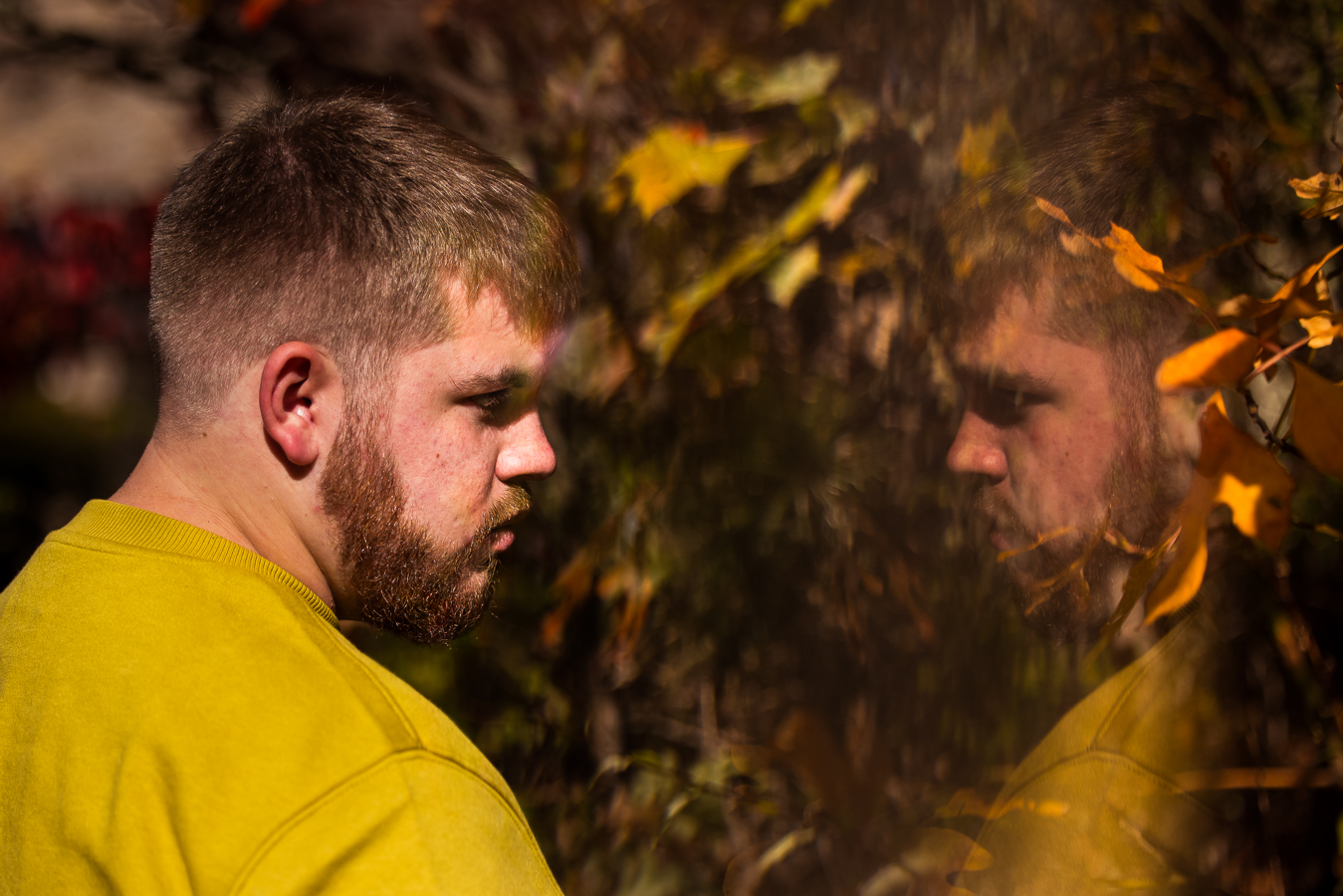 creative portrait photographer, lisa rhinehart, captures this unique, reflective image of this senior as he stares at a reflection of himself and the vibrant fall foliage found ontop of kings gap mansion 