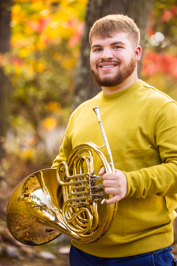 traditional portrait of this senior as he smiles at the camera while holding his french horn at kings gap mansion in central pa 