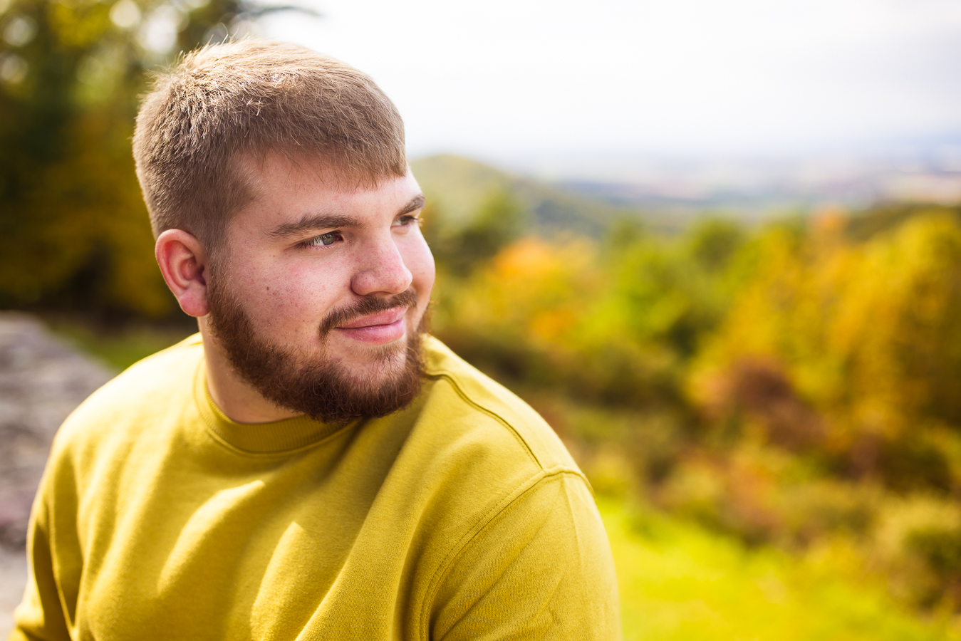 traditional portrait of this male with cerebral palsy at kings gap mansion as he sits on the overlook and watches off into the distance looking at the vibrant, colorful full foliage