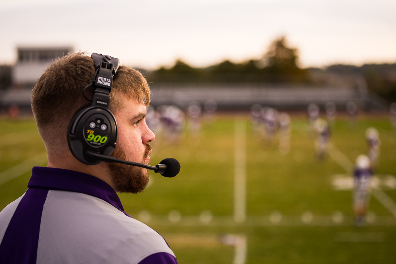 creative, unique image of this high school football coach as he is coaching the players and wearing his headset during this authentic portrait session at northern high school in pa 