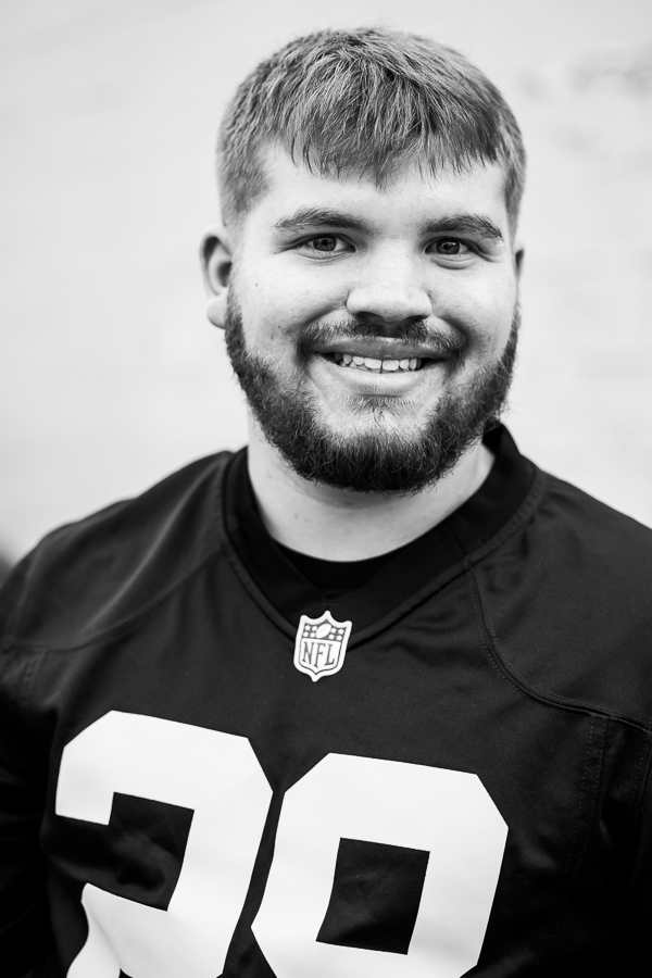 black and white traditional portrait of this senior with cerebral palsy as he smiles at the camera while wear a football jersey for this fun portrait session 