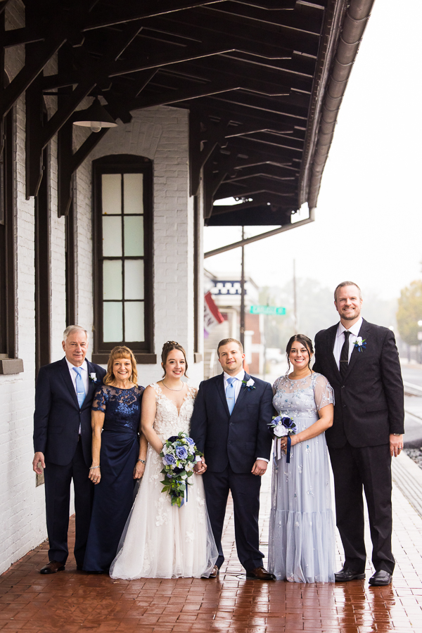 traditional family portrait of the bride and groom in the middle and their families on either side of them taken at the lincoln railroad station in central pa