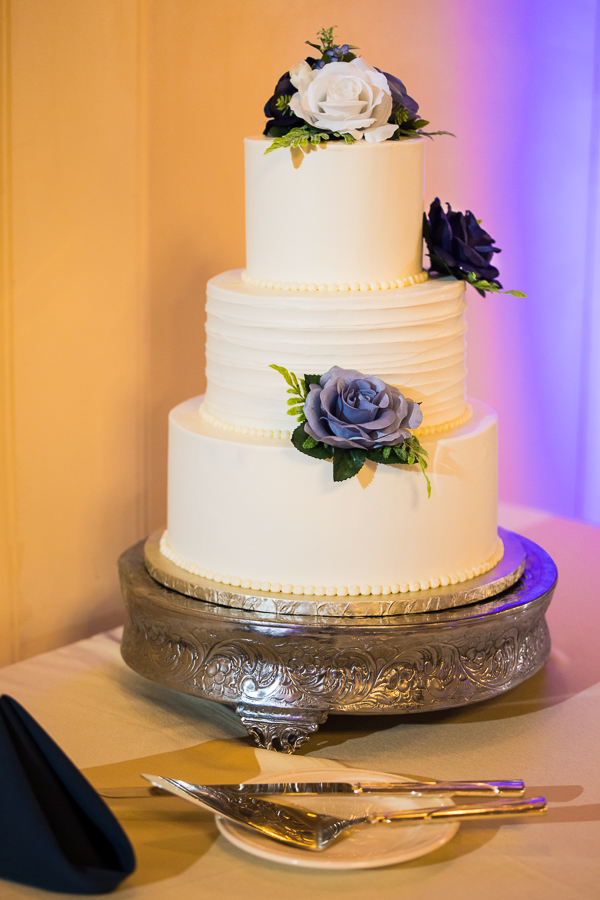 traditional detail image of the couples wedding cake featuring white, lavender and dark purple flowers 