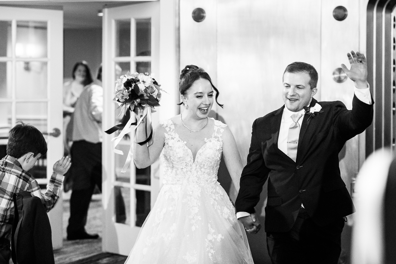 black and white image of the bride and groom as they smile and laugh as they enter into their Gettysburg hotel wedding reception 