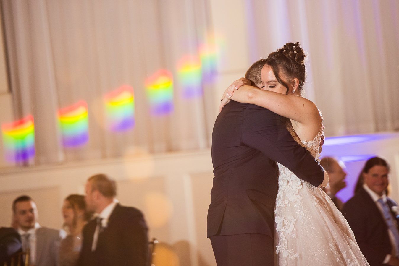 candid moment captured by wedding photographer, lisa rhinehart, as the bride and groom hug one another during their first dance together at their historical wedding venue in pennsylvania
