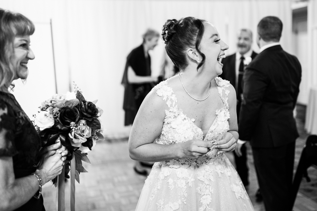 black and white candid moment of the bride as she smiles and laughs at guests captured by photojournalism photographer, lisa rhinehart
