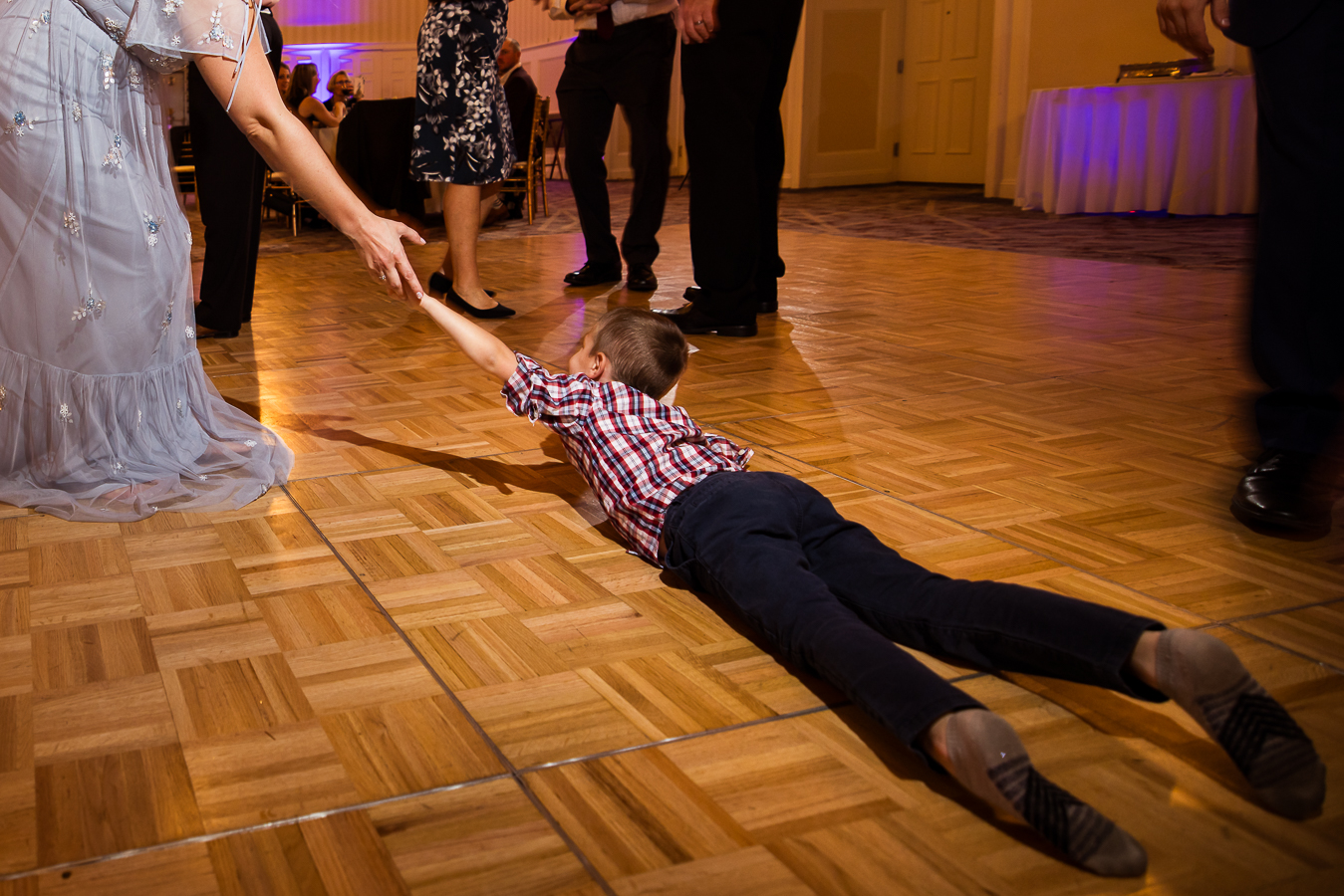 candid portrait photographer, lisa rhinehart, captures this moment of the young boy as he lays on the Gettysburg hotel dance floor and asks for help to stand up during this wedding reception 