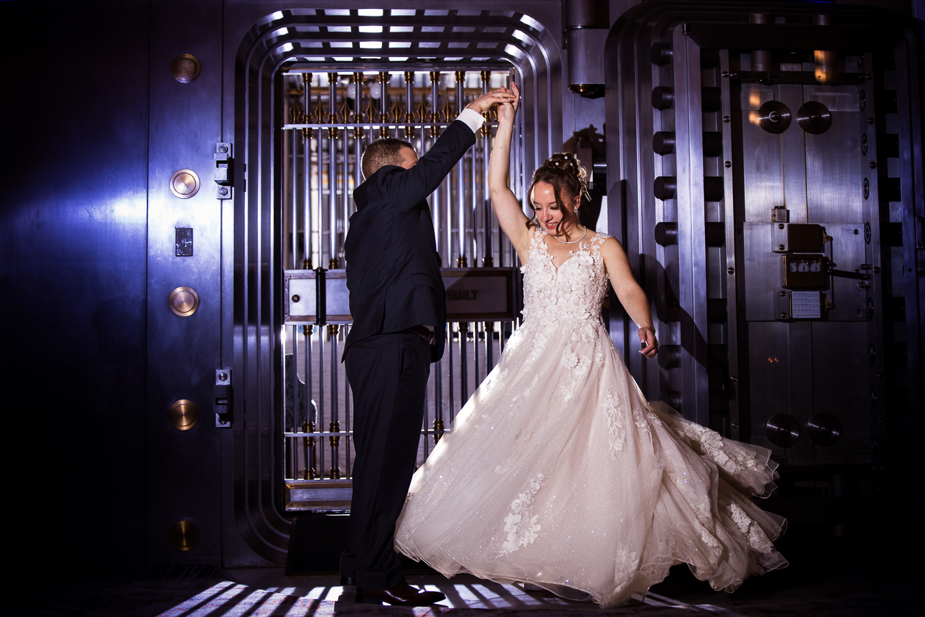 gettysburg wedding photographer, lisa rhinehart, captures this unique end of the night shot of the bride and groom as they stand in front of the historic bank vault inside of the Gettysburg hotel as the groom spins the bride around during their central pa wedding reception 