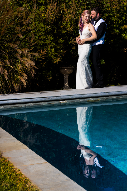 creative Murray Hill wedding photographer, lisa rhinehart, captures this image of the bride and groom hugging and laughing with one another while standing beside the reflecting pool located at Murray hill in Virginia with their reflection captured as well