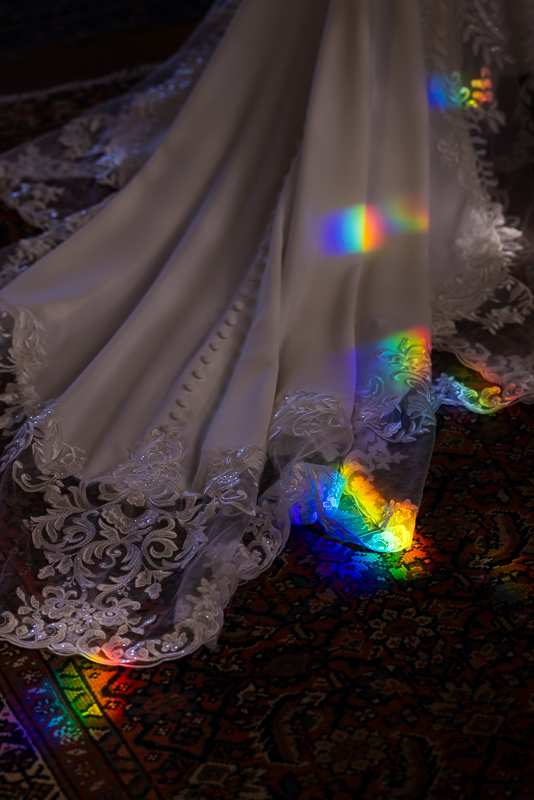 creative, colorful image of the bride's wedding dress with colorful, vibrant rainbow prisms featured on the dress
