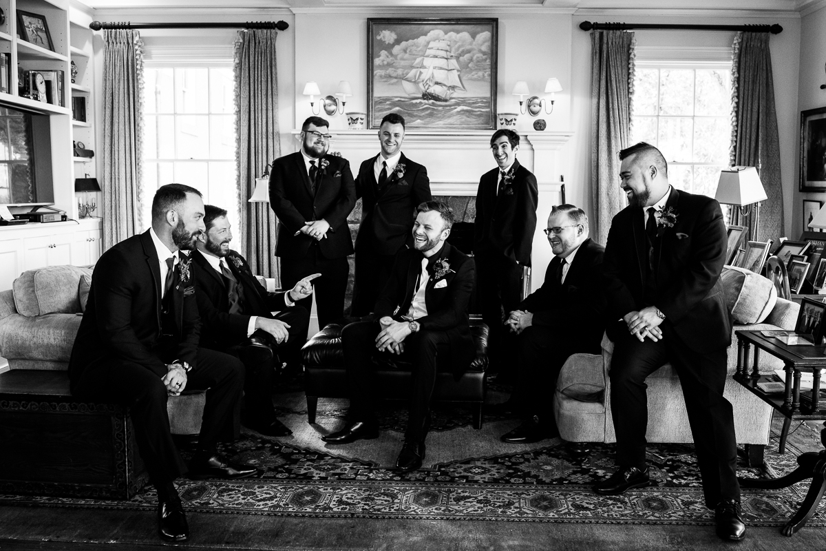 black and white image of the groom with the groomsmen laughing inside of Murray hill virginia before this outdoor fall wedding ceremony 