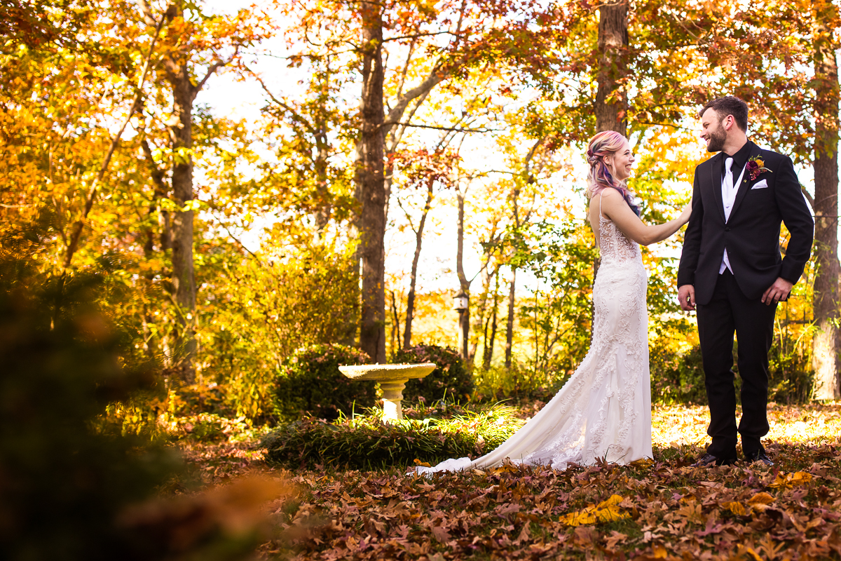 virginia wedding photographer, lisa rhinehart, captures this vibrant colorful outdoor fall first look of the bride and groom as they smile at each other surrounded by the fall foliage of leesburg va