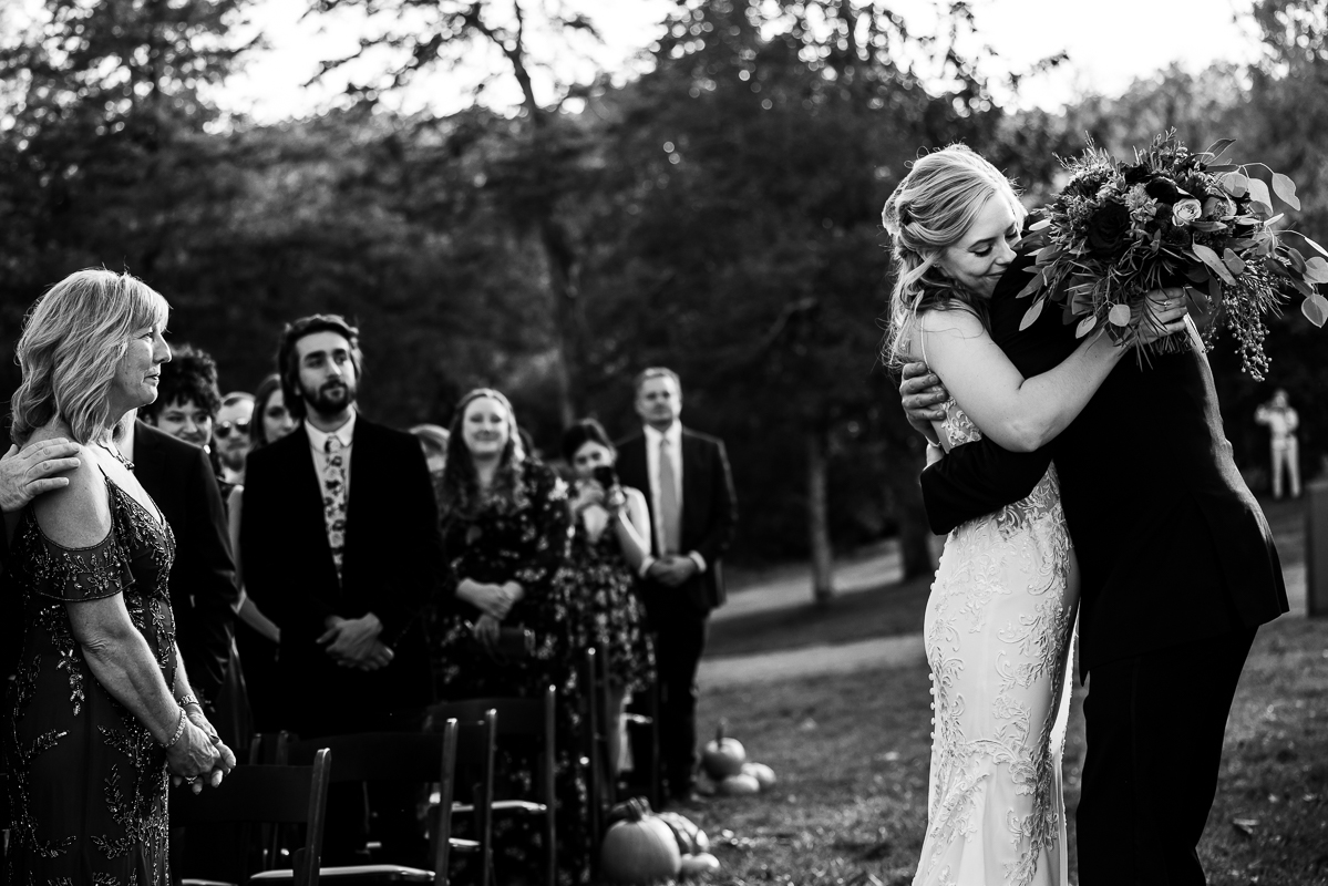 candid, authentic wedding photographer, lisa rhinehart, captures this emotional moment between bride and her dad as they share a hug at the end of the aisle before starting this outdoor fall wedding ceremony in Leesburg va by the Potomac river