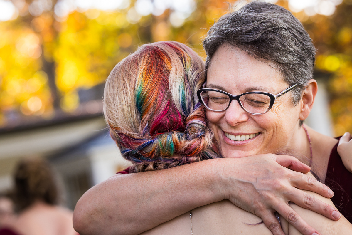 vibrant, colorful image of the back of the brides rainbow hair as she hugs her family members after this outdoor wedding ceremony in Virginia 