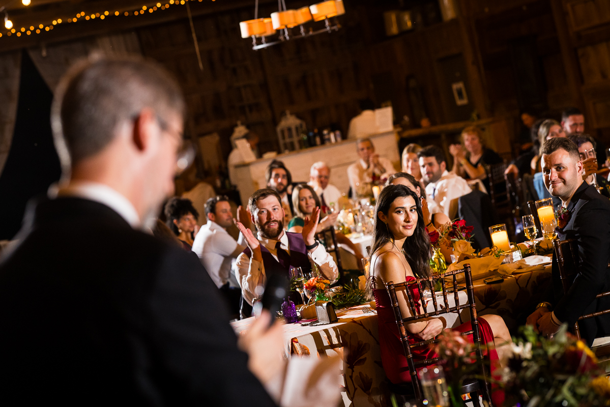 candid image of the guests as they watch the family and friends give speeches at this barn wedding reception at Murray hill wedding venue 