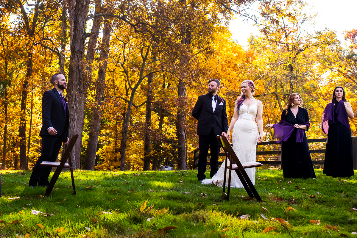 behind the scenes image of the bride, groom and their wedding party as they get ready to pose for their vogue vaniety fair shot before this outdoor vibrant fall wedding reception