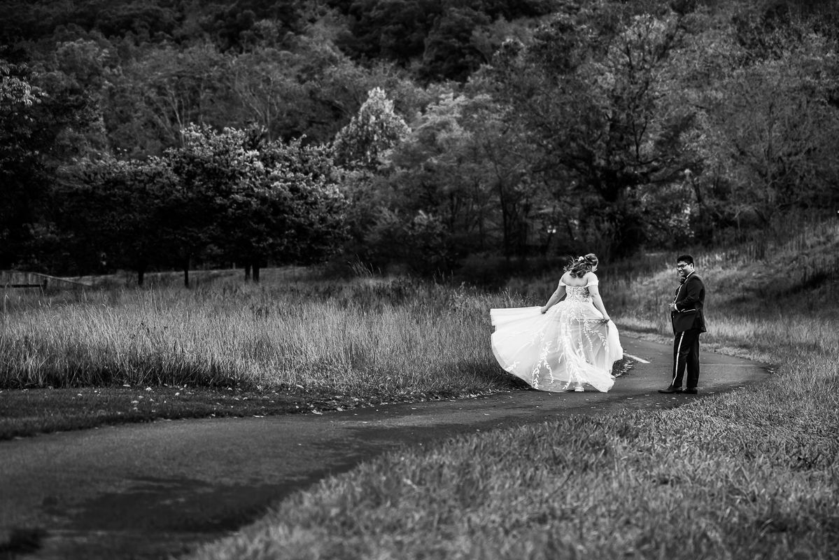 Black and white image of the bride and groom as they walk down a pathway with the fall foliage surrounding them during these outdoor romantic portraits captured by creative Omni wedding photographer, lisa rhinehart