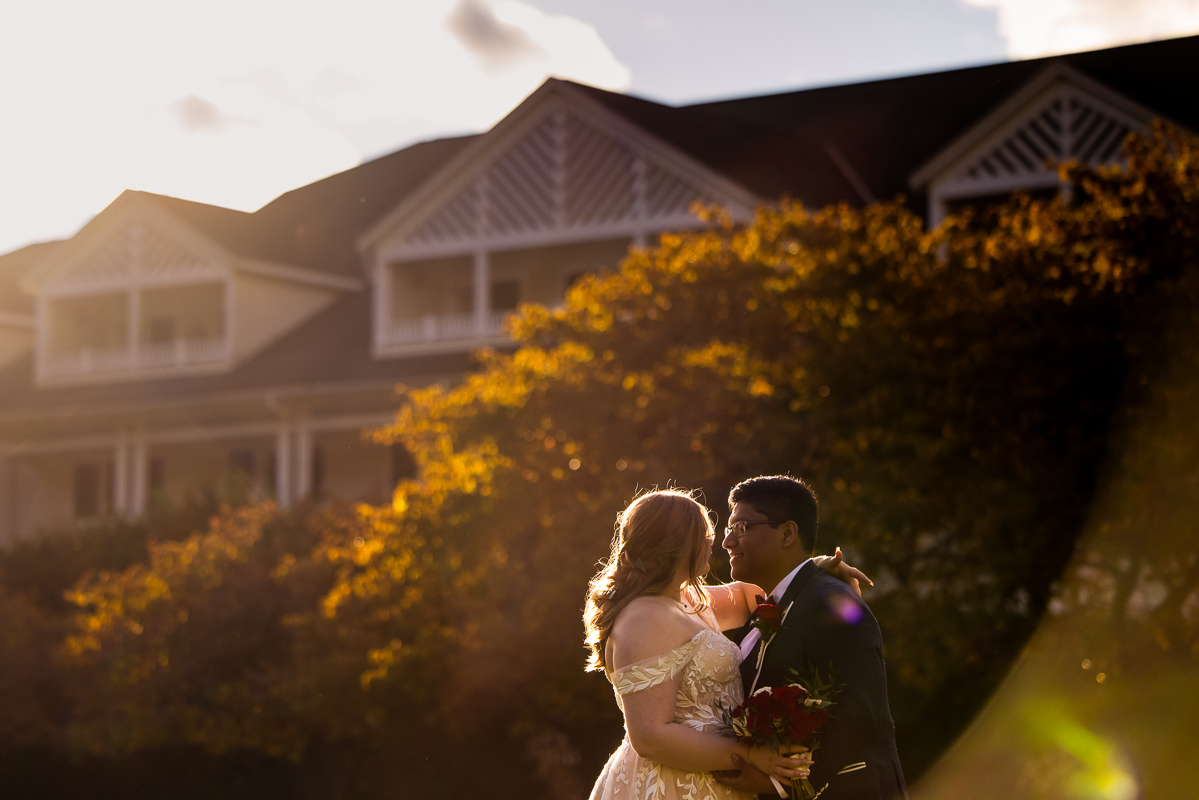creative Omni wedding photographer, lisa rhinehart, captures this golden hour romantic portrait of the bride and groom as they almost kiss in the sunlight beam outside of the omni bedford springs in Bedford pa 