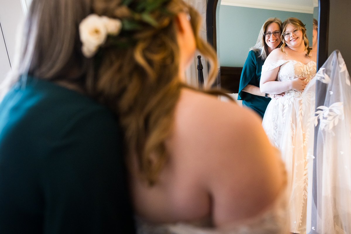 creative Omni wedding photographer, lisa rhinehart, captures this unique, creative image of the bride and her mom and they share a hug and smile at one another in the mirror captured through the mirrors reflection 