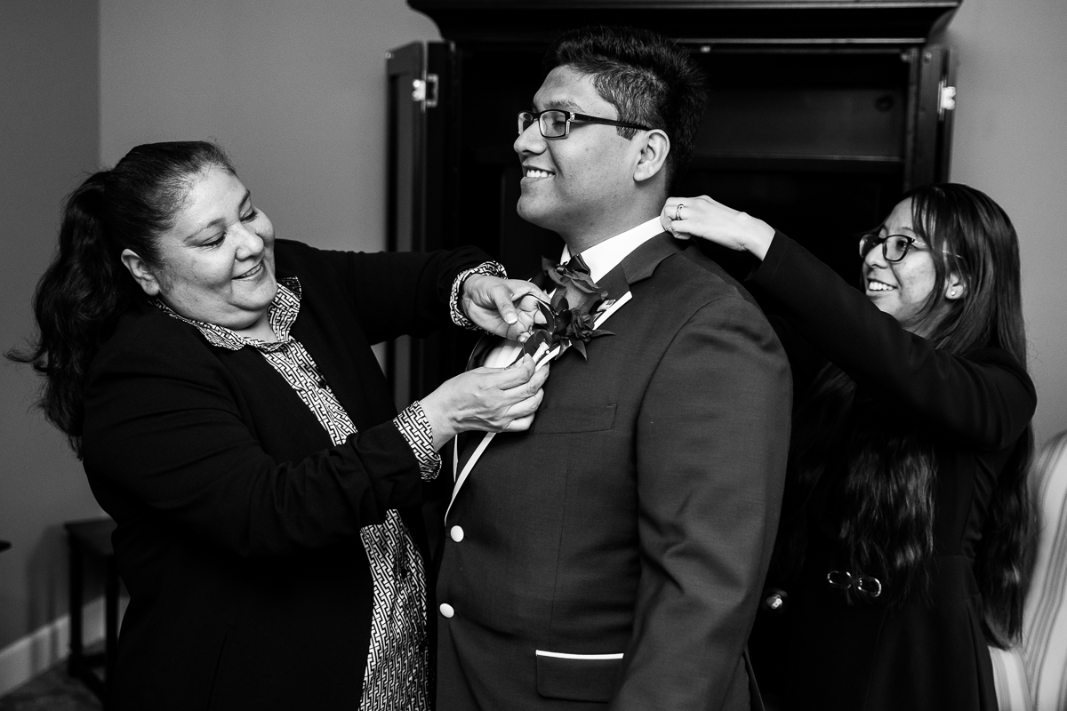black and white image of the groom as he gets ready with the help of his family before his wedding ceremony at the omni at bedford springs in Bedford, pa captured by best pa wedding photographer, lisa rhinehart
