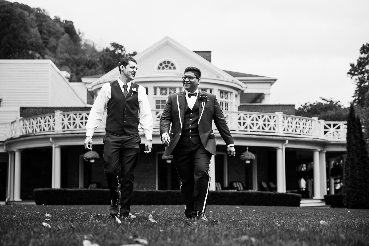 black and white image of the groom and his best man as they walk across the lawn at the omni bedford springs in Bedford, pa before his wedding ceremony captured by creative pa wedding photographer, lisa rhinehart