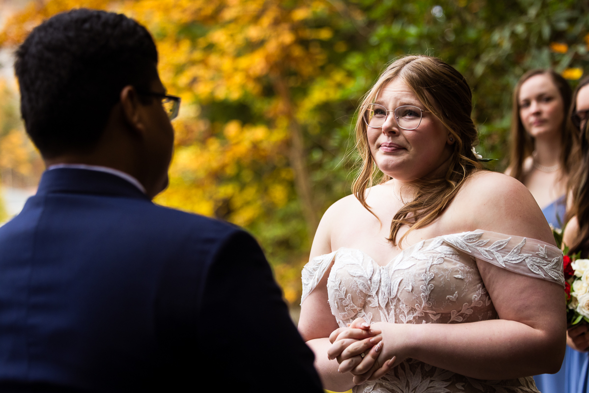 creative Omni wedding photographer, lisa rhinehart, captures this emotional, authentic moment of the bride as she holds back tears during her vibrant, colorful, outdoor fall wedding ceremony in Bedford, pa 