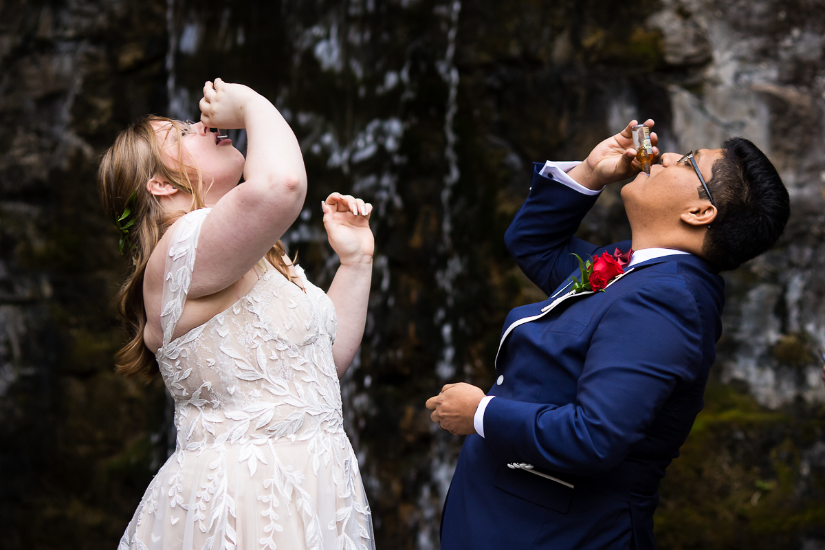 fun pa wedding photographer, lisa rhinehart, captures this fun end of the ceremony shot of the bride and groom as they take a shot at the end of their outdoor fall wedding ceremony in front of the waterfall at omni bedford springs wedding venue 