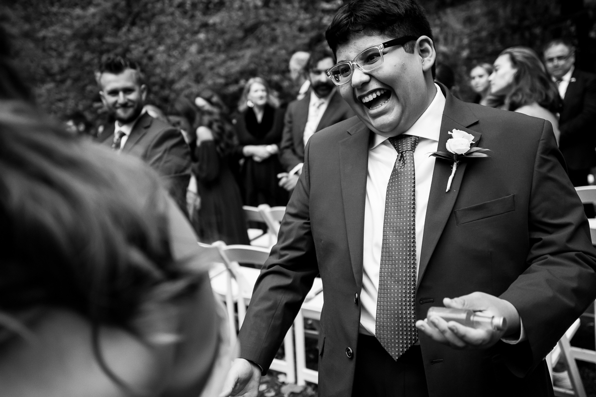 black and white image of the grooms sibling as he laughs and smiles at the end of this outdoor wedding ceremony in Bedford pa 