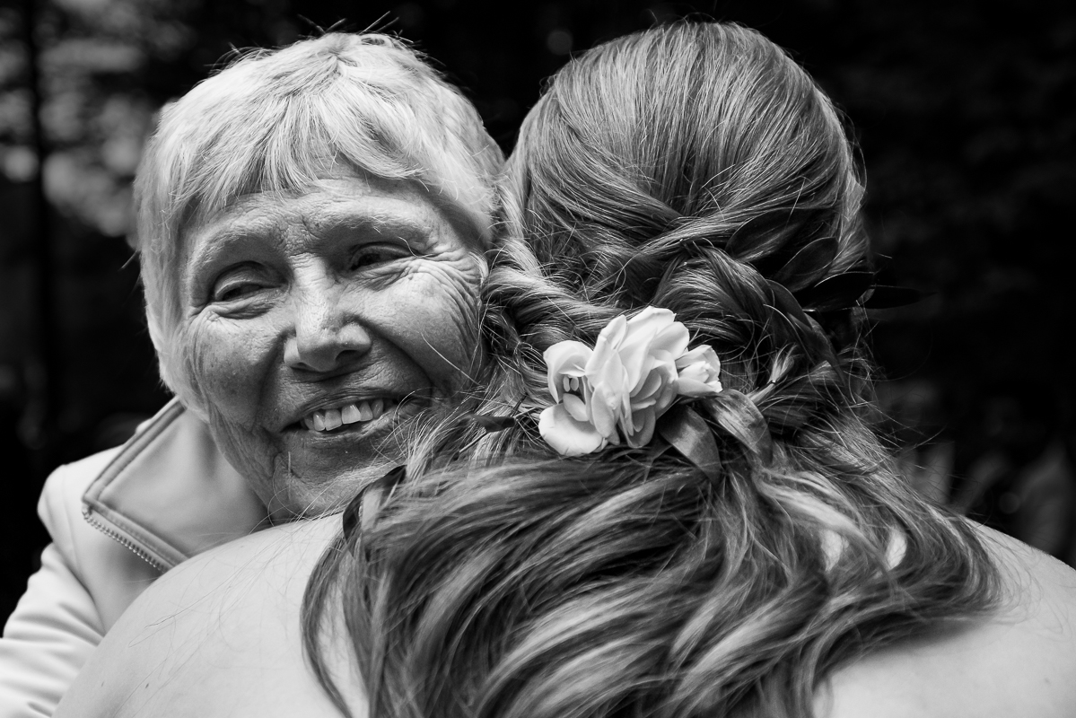 omni bedford springs wedding photographer, lisa rhinehart, captures this black and white authentic, emotional moment of the bride as she hugs her grandma at the end of this outdoor wedding ceremony in Bedford springs, pa 