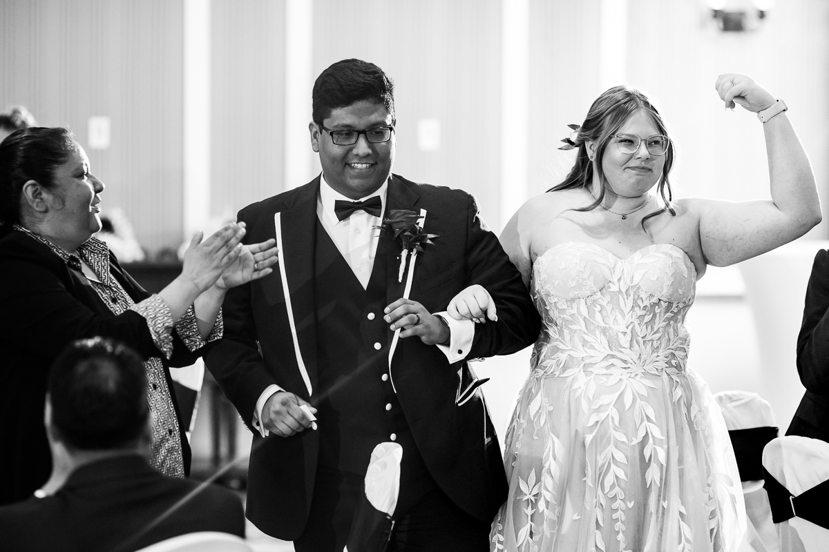 fun pa wedding reception photographer, lisa rhinehart, captures this black and white image of the bride and groom as they walk into their indoor wedding reception located at the omni bedford springs 