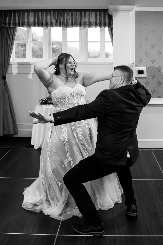 creative Omni wedding photographer, lisa rhinehart, captures this fun, candid black and white image of the bride and her father as they share a fun dance together during this indoor wedding reception at the omni bedford springs resort in Bedford pa 
