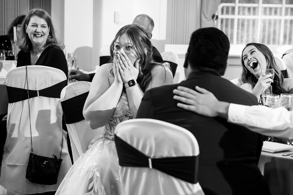 creative Omni wedding photographer, lisa rhinehart, captures this candid black and white image of the bride as she laughs and covers her face during the speeches part of this wedding reception at the omni in Bedford pa 