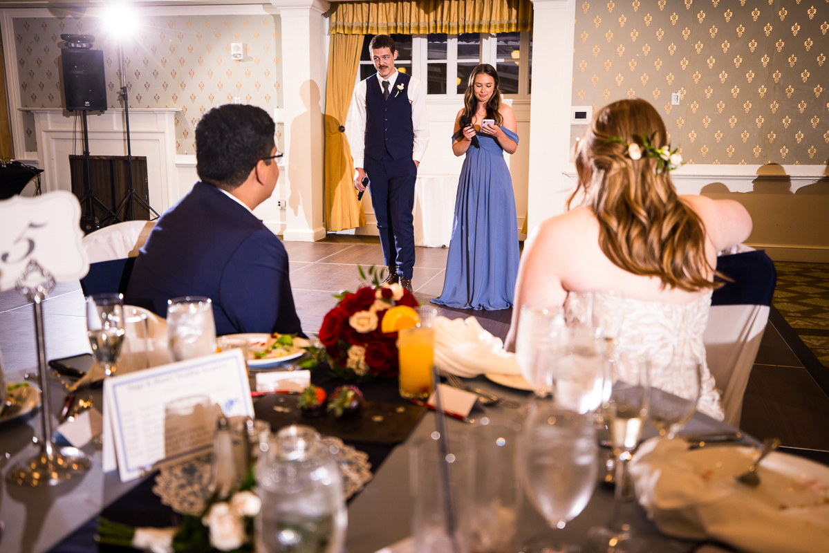 pa wedding photographer, lisa rhinehart, captures this image of the best man and bridesmaid as they share their speeches during the wedding traditions portion of the wedding reception at omni bedford springs in pa 