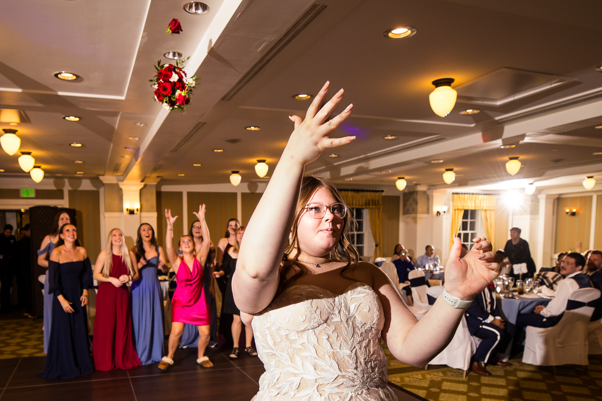 pa wedding photographer, lisa rhinehart, captures the moment when the bride throws her bouquet during the wedding traditions portion of their wedding reception in Bedford, pa 