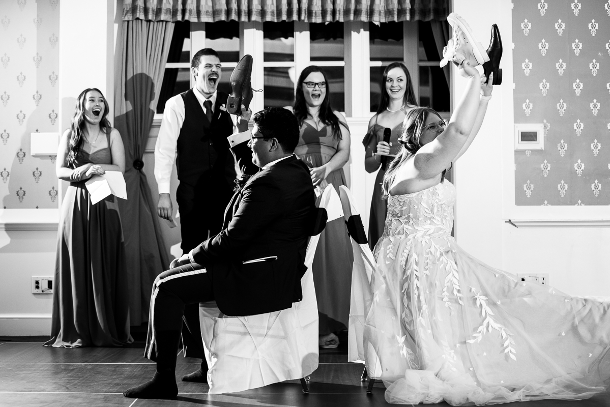 black and white image of the bride and groom as they play the shoe game during the wedding reception at the omni bedford springs resort, pa 