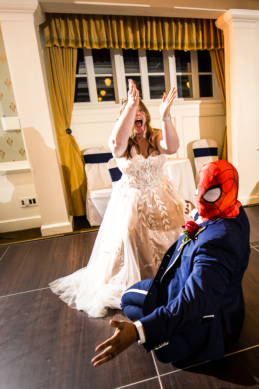 creative Omni wedding photographer, lisa rhinehart, captures this fun, unique image of the bride as she cheers for her husband who is wearing a spiderman mask after grabbing the garter during this unique, fun wedding reception at the omni in Bedford pa 