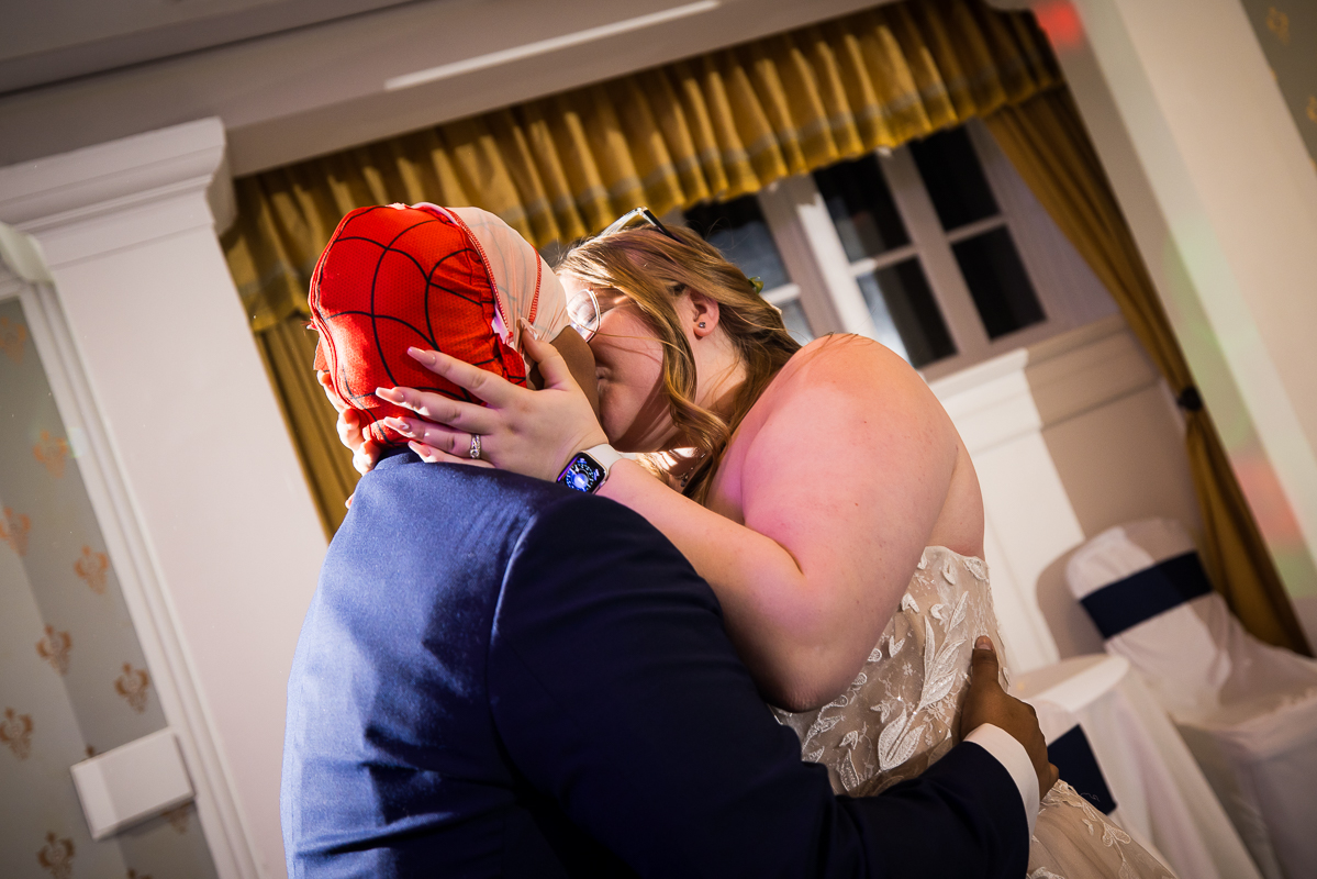omni bedford springs wedding photographer, lisa rhinehart, captures the moment when the bride kisses her groom after taking off his spiderman mask during this fun unique wedding reception 