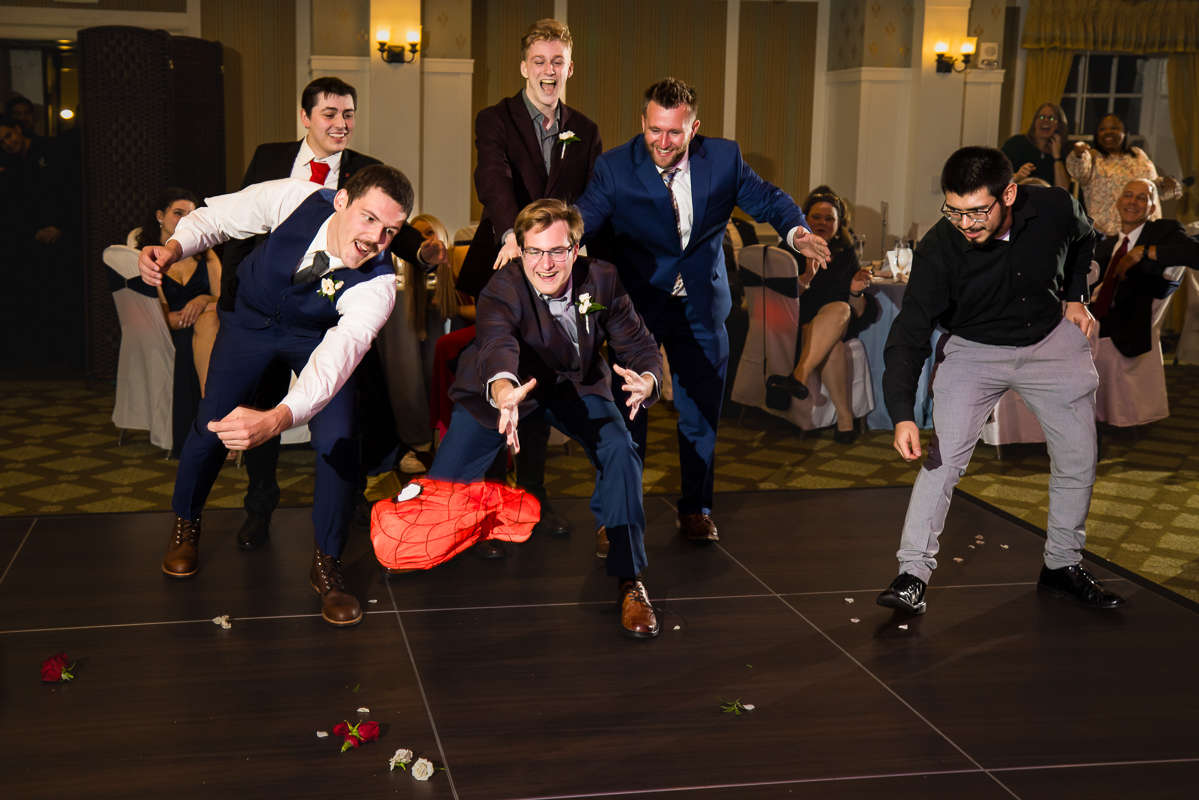 unique fun image of the male guests at the wedding reception trying to catch the spiderman mask captured by wedding photographer, lisa rhinehart 