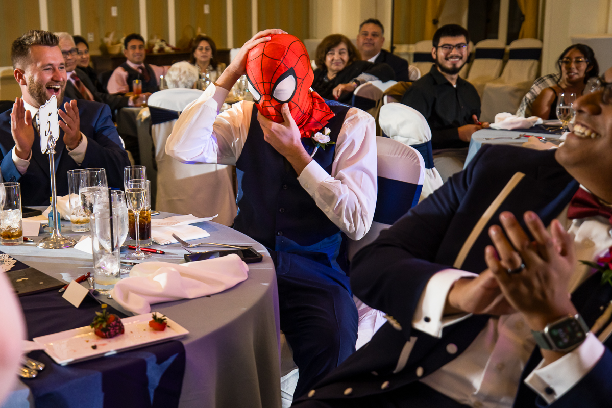 omni bedford springs wedding photographer, lisa rhinehart, captures this moment where the best man puts the spiderman mask on during this indoor wedding reception at the omni bedford spring resort 