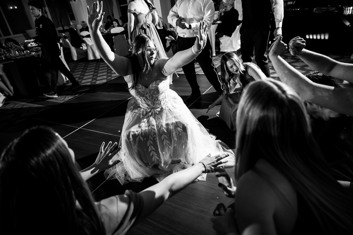 fun pa wedding reception photographer, lisa rhinehart, captures this black and white image of the bride and her friends getting low on the dance floor during this fun wedding reception at the omni bedford springs resort in pa 