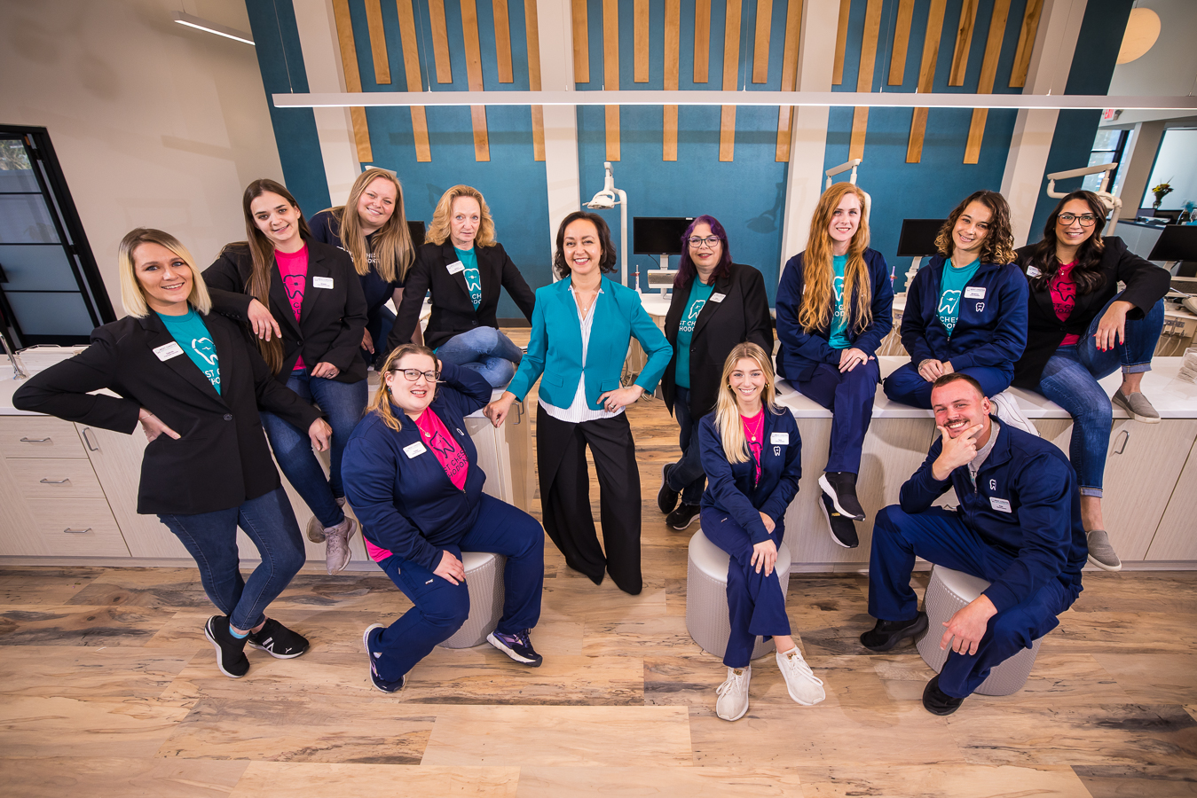 commerical photographer, lisa rhinehart captures this image of west chester orthodontics full staff as they pose together and smile at the camera while wearing vibrant teal and fuschia colored tops