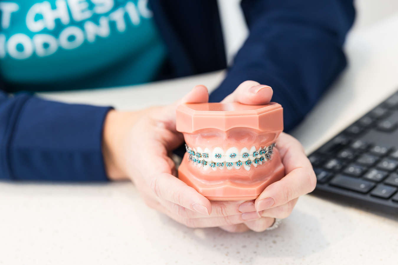 close up image of a tooth mold that is wear teal braces held by one of the staff members at this orthodontist office in Pennsylvania 