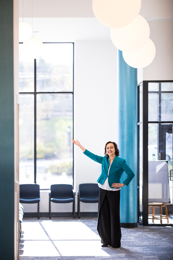 pa orthodontist, dr ferrell, as she stands in the lobby of her newly renovated space while holding her hand up to show off the fun, globe lighting captured by pa branding photographer, lisa rhinehart