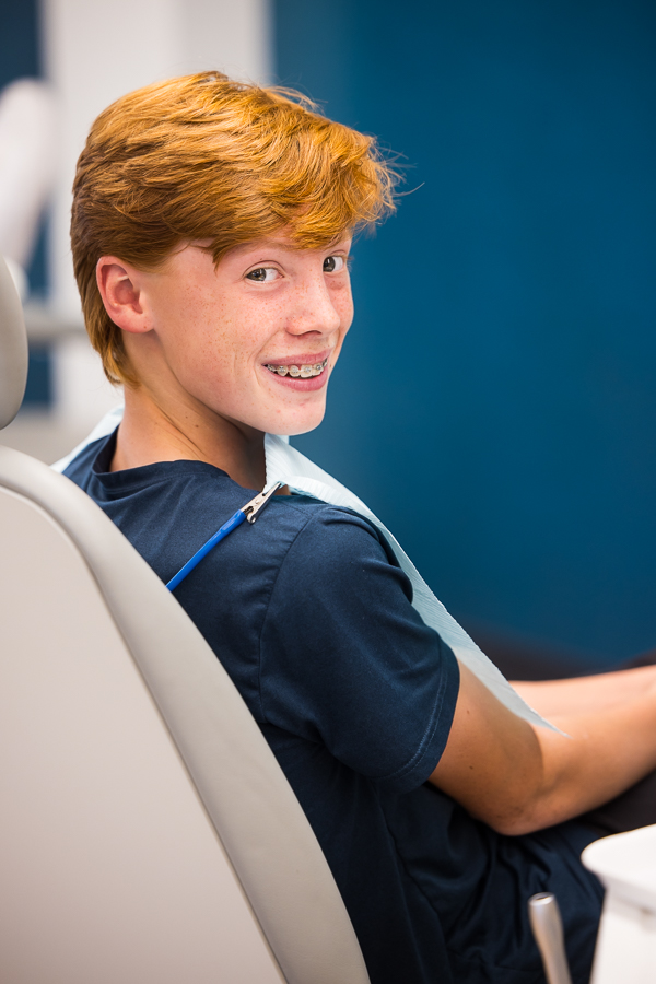 image of a patient as they sit in the chair and look over their shoulder at the camera during their orthodontist appointment in west chester pa during this branding photography session 