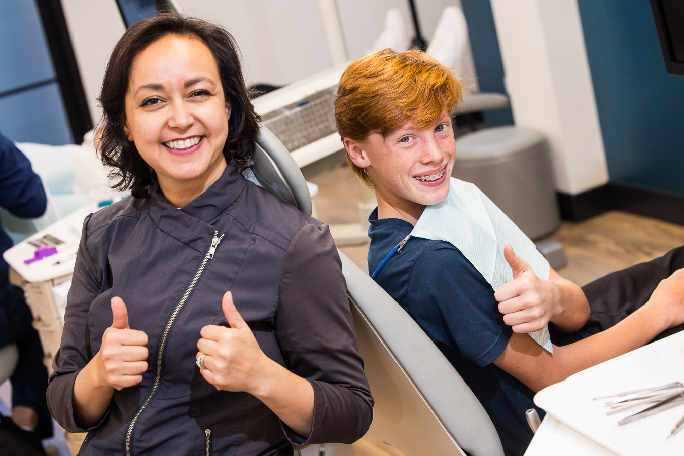 Social media content photography, captured by lisa rhinehart, featuring dr ferrell from west chester orthodontics and a teenager patient as they smile and give the thumbs up to the camera during their appointment 