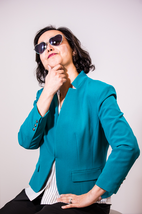 business branding photographer, lisa rhinehart, captures this fun, vibrant image of dr ferrell as she wears heart shaped sunglasses and poses wearing her teal jacket for this creative imagery for women entrepreneurs