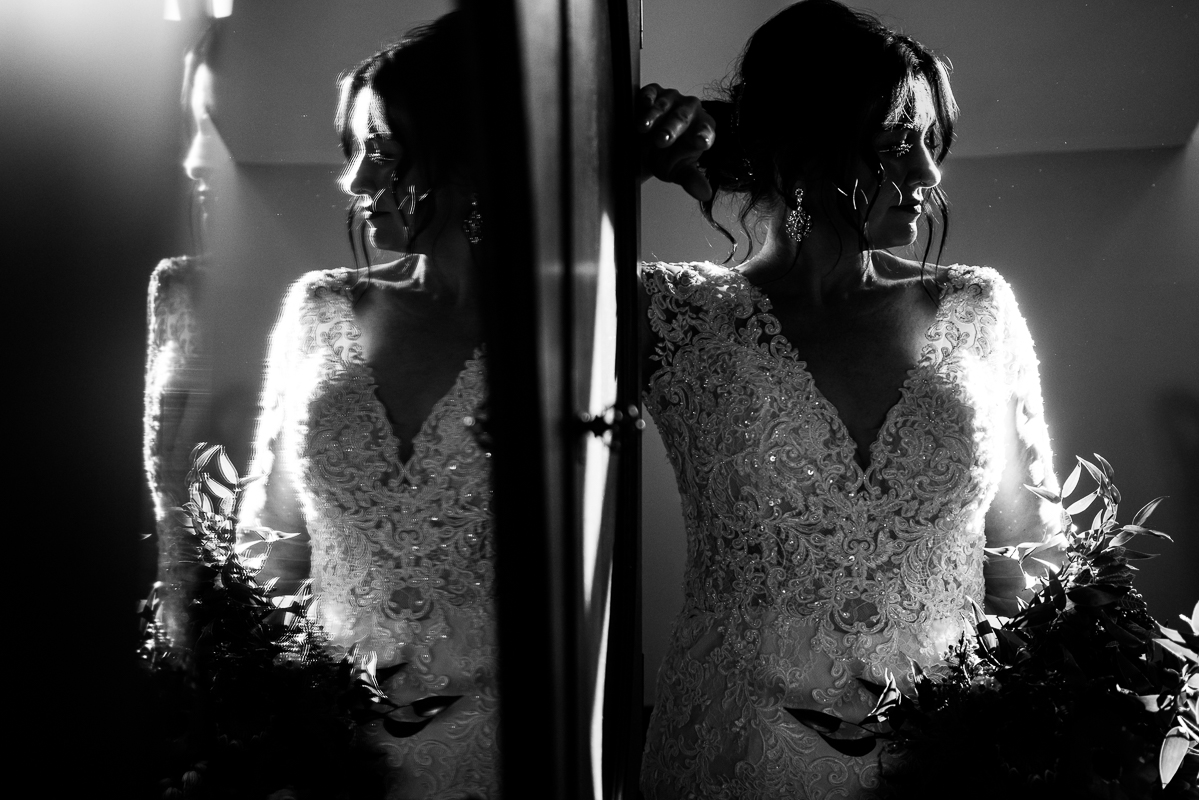 best creative pa wedding photographer, lisa rhinehart, captures this stunning creative black and white image of the bride as she stands beside the mirror and looks off into the distance during her bridal portraits before her outdoor Christmas wedding ceremony 
