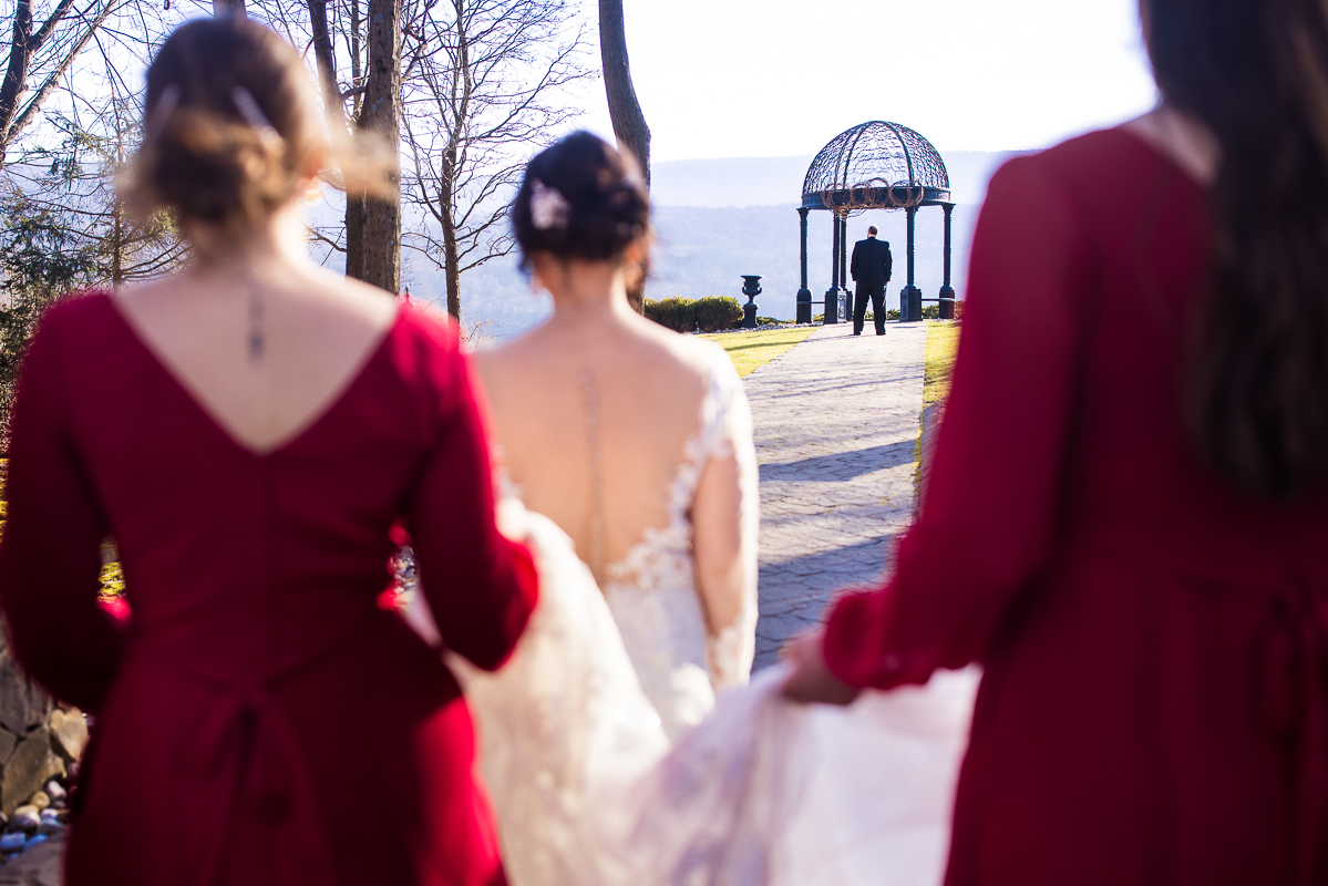 Candid wedding photographer, lisa rhinehart, captures the moment of the bride walking up behind her groom before their first look at ridgecrest at stroudsmoor country inn before their winter wedding ceremony